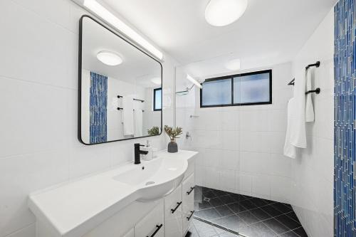 a white bathroom with a sink and a mirror at Summer Cove on the Ocean with Pool in Coolum Beach