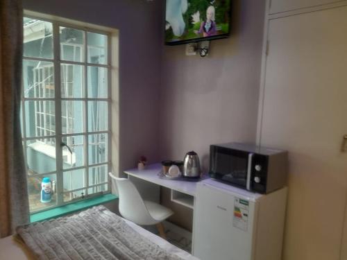 a small kitchen with a microwave and a desk with a microwave at B&P Guesthouse in Boksburg