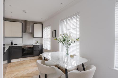 a kitchen with a glass table and white chairs at Glebe Road in Chelmsford