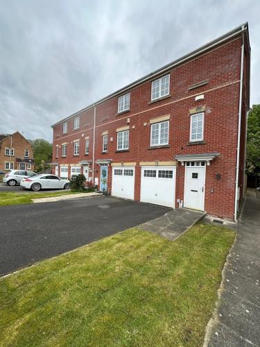 a large red brick building with white garage doors at Mmc serviced accommodation 2 in Leigh