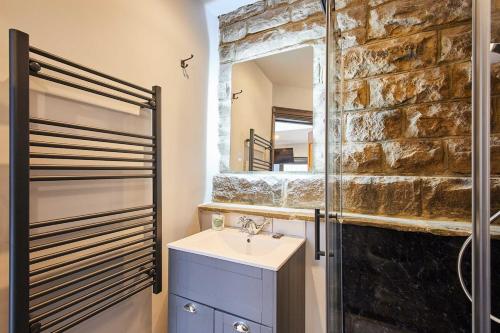 a bathroom with a sink and a stone wall at The Churchside Well in Ravenscar
