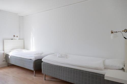 a bed in a room with a white wall at Strömbäcks Vandrarhem in Umeå