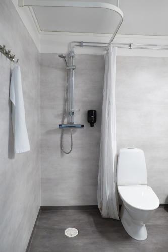 a bathroom with a white toilet and a shower at Strömbäcks Vandrarhem in Umeå