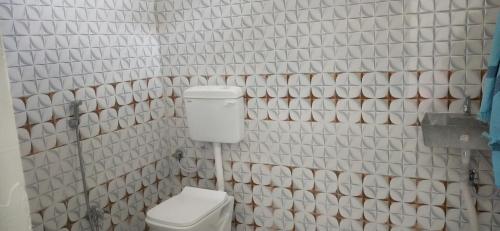 a white tiled bathroom with a toilet and a sink at Pie Restuarant and HomeStay in Baihar