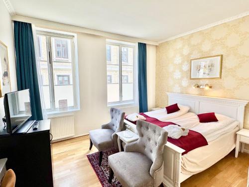 a bedroom with a bed and two chairs and a television at Hotel Concordia in Lund