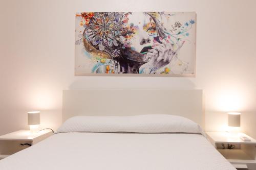 a bedroom with a white bed with a painting above it at Casa do Lado, Flores Açores in Lajes das Flores