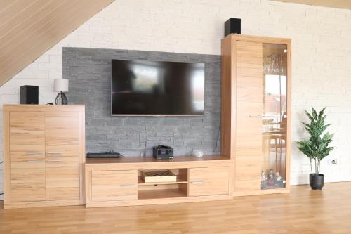 a large wooden entertainment center with a tv on a brick wall at Siggis-Ferienwohnung in Bad Wildungen