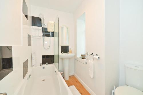 a white bathroom with a tub and a sink at Ardmore House in Ventnor