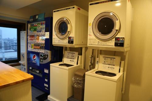 a laundry room with three washing machines on display at Hotel New Station in Matsumoto