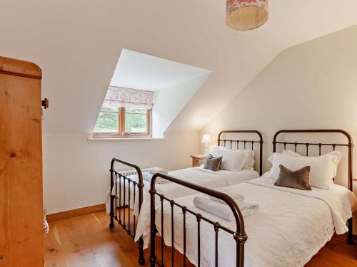 two beds in a white room with a window at 4 Bed in Frome oc-27808 in Holwell