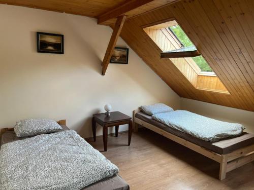 two beds in a room with wooden ceilings at Dom Acapulco in Kromszewice