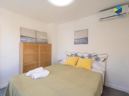 a bedroom with a bed with yellow and white pillows at Can Tassi in Porto Cristo