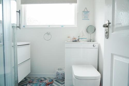 a bathroom with a toilet and a sink and a window at Chalet 80 in Sandown