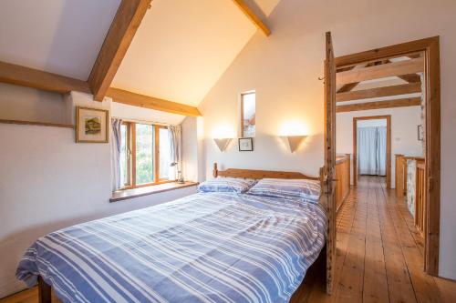 a bedroom with a bed with a blue striped comforter at Crabhall Barn in Haverfordwest