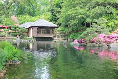 ein Garten mit einem Haus und einem Teich mit Blumen in der Unterkunft Best Western Hotel Kaiserslautern in Kaiserslautern
