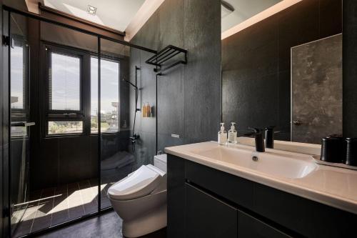 a bathroom with a sink and a toilet and a glass shower at 藤夏日光 in Weiqian