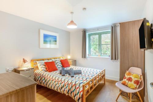 a bedroom with a bed with orange pillows and a window at 3 Bed in Winnards Perch oc-m30557 in Saint Columb Major
