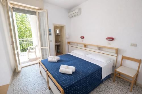 a bedroom with a bed and a chair and a window at Camere Capinera in Cesenatico