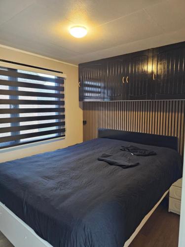 a bedroom with a large bed with a blue comforter at Houten Chalet nabij Beekse Bergen in Hilvarenbeek