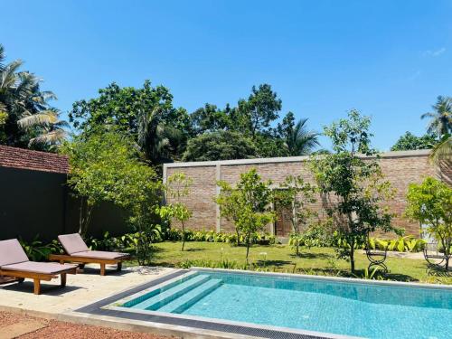 a swimming pool in a yard with two chairs and a building at Dhyana Beach Villa in Ambalangoda