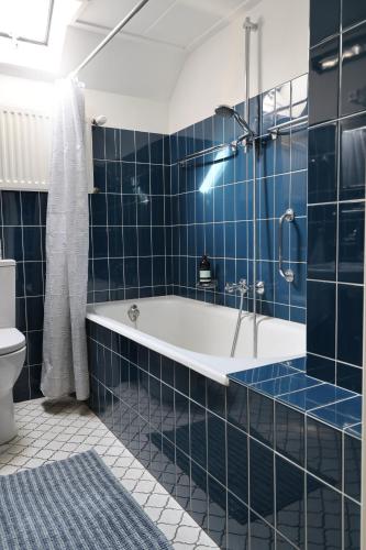a blue tiled bathroom with a tub and a shower at De Fazant in Laren