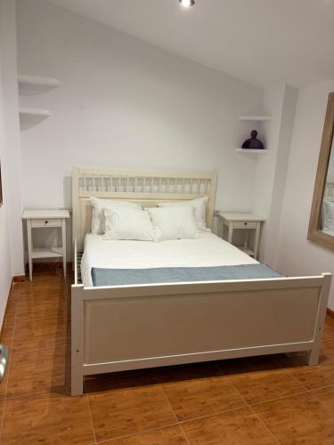 a bed with white sheets and pillows in a room at Ático centro Benicasim in Benicàssim