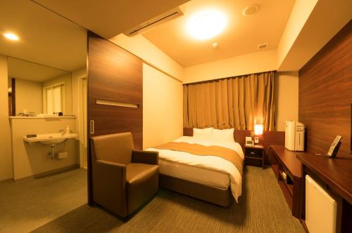 ein Hotelzimmer mit einem Bett und einem Stuhl in der Unterkunft Dormy Inn Himeji Natural Hot Spring in Himeji