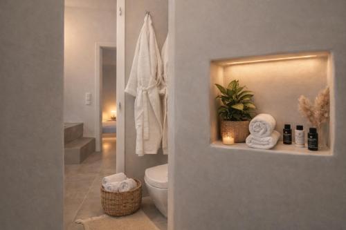 a bathroom with a toilet and towels on a shelf at Villa Andalusia, Steps from Orkos Beach in Naxos Chora