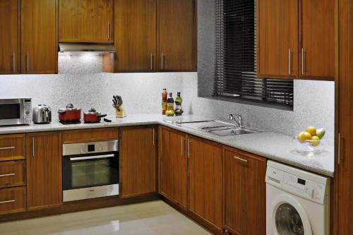 a kitchen with wooden cabinets and a sink and a dishwasher at Ramada by Wyndham Downtown Dubai in Dubai
