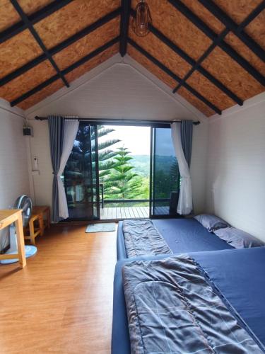 a bedroom with a bed and a large window at บ้านพัก เย็นเย็นแคมป์ปิ้ง อิน เขาค้อ in Ban Pa Daeng