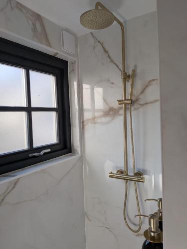 a shower in a bathroom with a window at Onder de Oude Walnoot in Sint Pancras