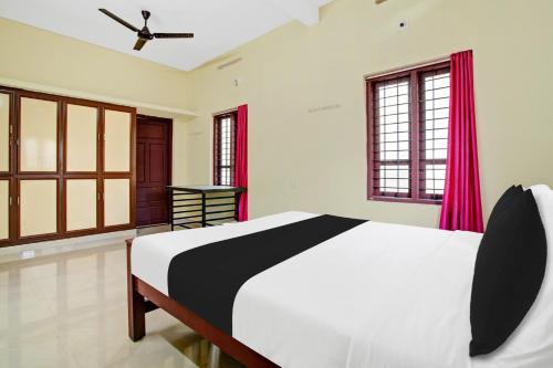 a bedroom with a large bed with red curtains at Hotel O Nakshathra Inn in Kazhakuttam