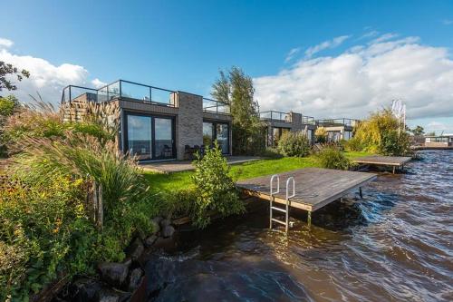 a house with a wooden dock in the water at Vakantiepark De Wiedense Meren in Wanneperveen