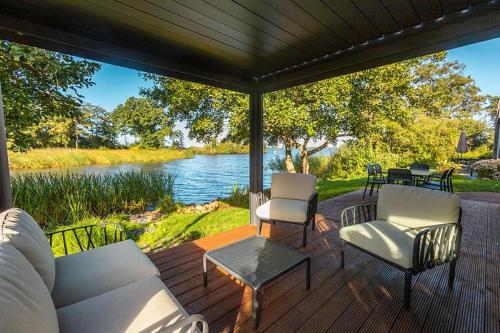 a covered deck with chairs and a table and water at Vakantiepark De Wiedense Meren in Wanneperveen
