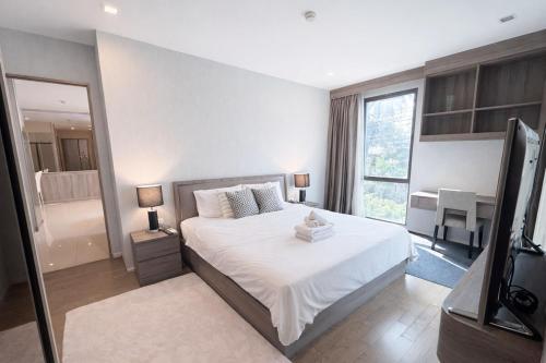 a bedroom with a white bed and a large window at Spacious 2BR Condo with 2 Balconies in Sukhumvit16 in Bangkok