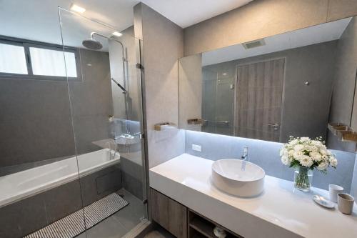 a bathroom with a sink and a shower and a mirror at Spacious 2BR Condo with 2 Balconies in Sukhumvit16 in Bangkok