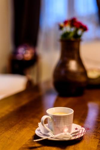 a cup of coffee on a table with a vase at Alexander House in Deva