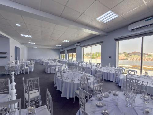 a room filled with tables and chairs with white linens at Peregrine Hotel Jos in Jos