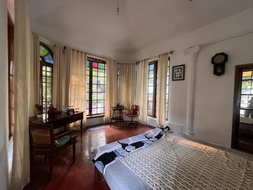 a bedroom with a bed and a desk and windows at Fort flora in Cochin