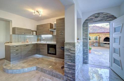 a large kitchen with a fireplace and a door at Apartments Velebit house in Biljevine