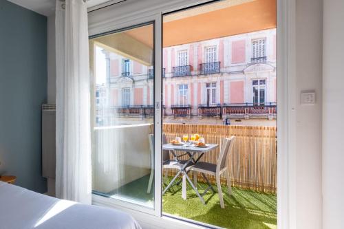 a bedroom with a view of a table and a balcony at La Pomponnette du Bassin in Arcachon