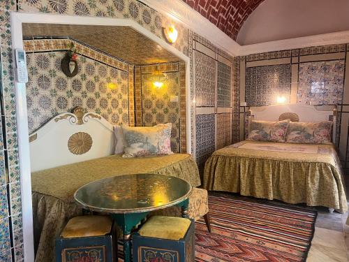 a room with two beds and a table in it at Hôtel Bou Fares in Sidi Bou Saïd