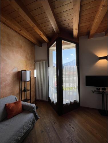 a living room with a couch and a large window at COZY LAKE COMO APARTMENTS in Valmadrera