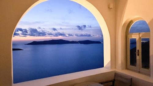 an arched window with a view of the ocean at Yposkafo Suites - Private Studio - Santorini in Fira