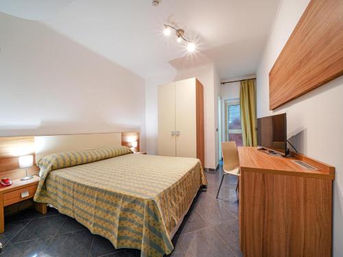 a bedroom with a bed and a desk and a television at Baia Tropea in Fitili