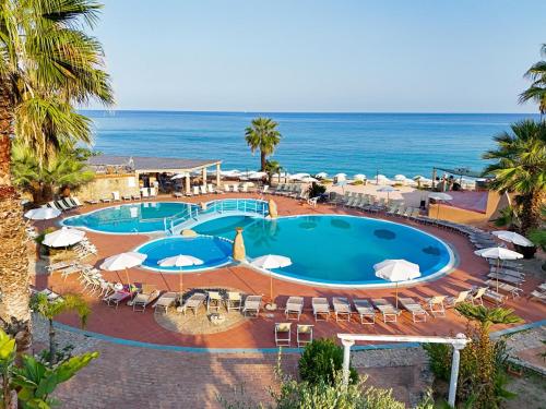 a pool with chairs and umbrellas and the ocean at Baia Tropea in Fitili