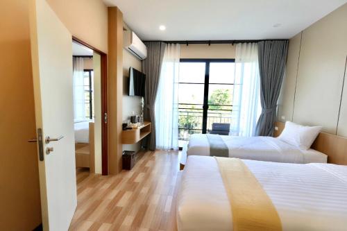 a hotel room with two beds and a window at KL Dawarika Mali Hotel in Ban Tai
