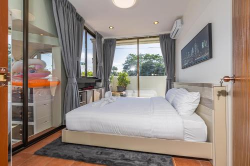 a bedroom with a white bed and a window at Villa Natali between Rawai and Nai Harn in Rawai Beach