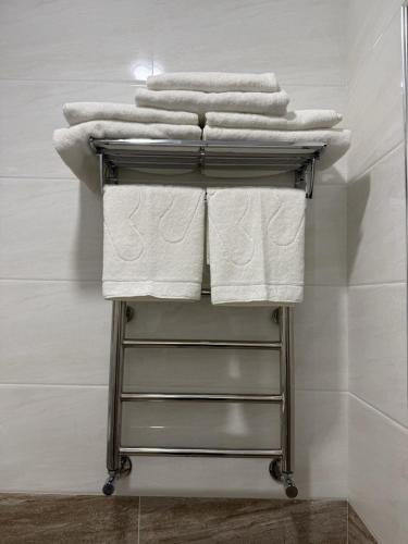 a pile of towels on a towel rack in a bathroom at Munir Hotel in Chilanzar