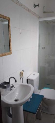 a bathroom with a sink and a toilet and a mirror at Apartamento de frente ao mar - Centro in Peruíbe